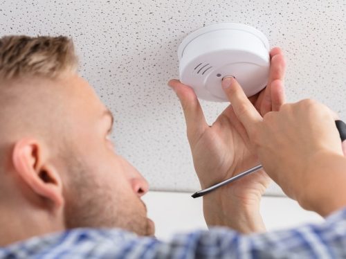 Low,Angle,View,Of,A,Person's,Hand,Installing,Smoke,Detector